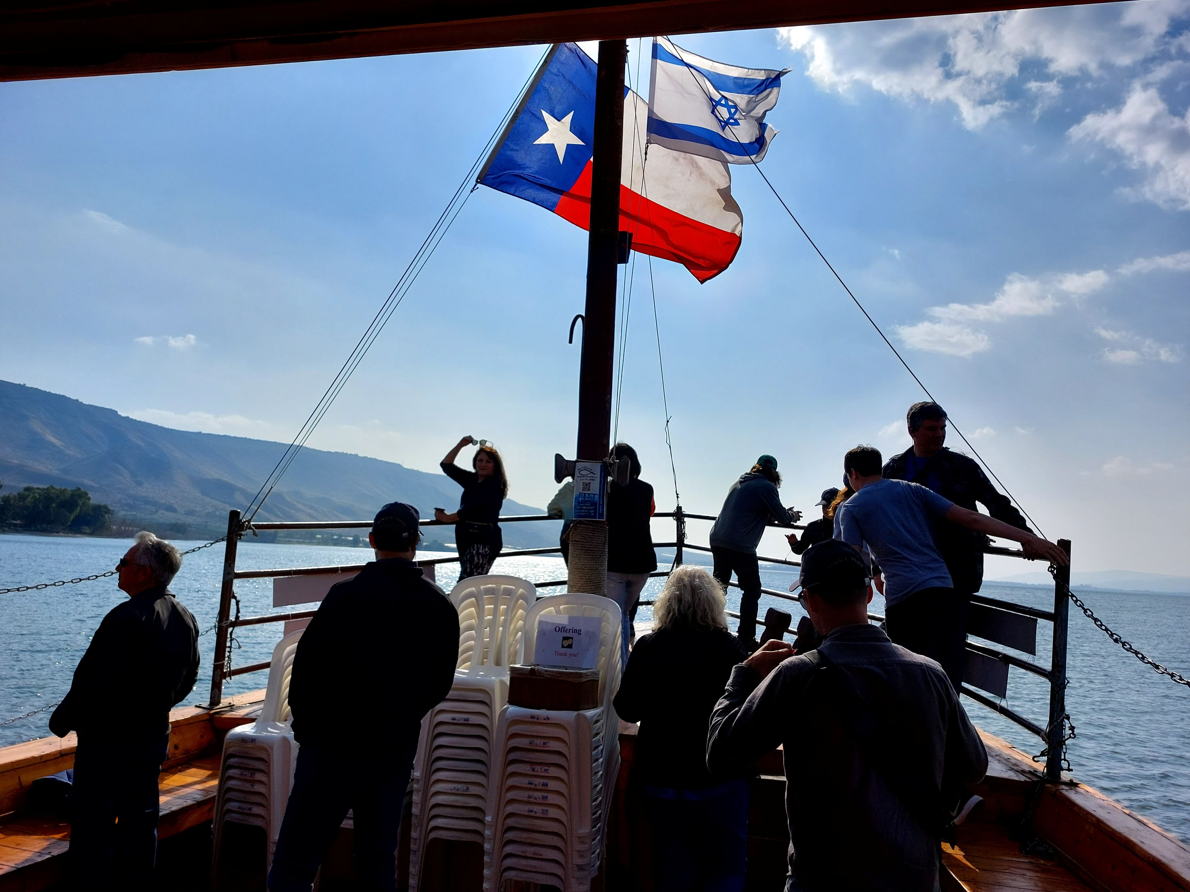 Tourists on a boat on the Sea of Galilee with the Texas flag and Israeli flag flying from the mast