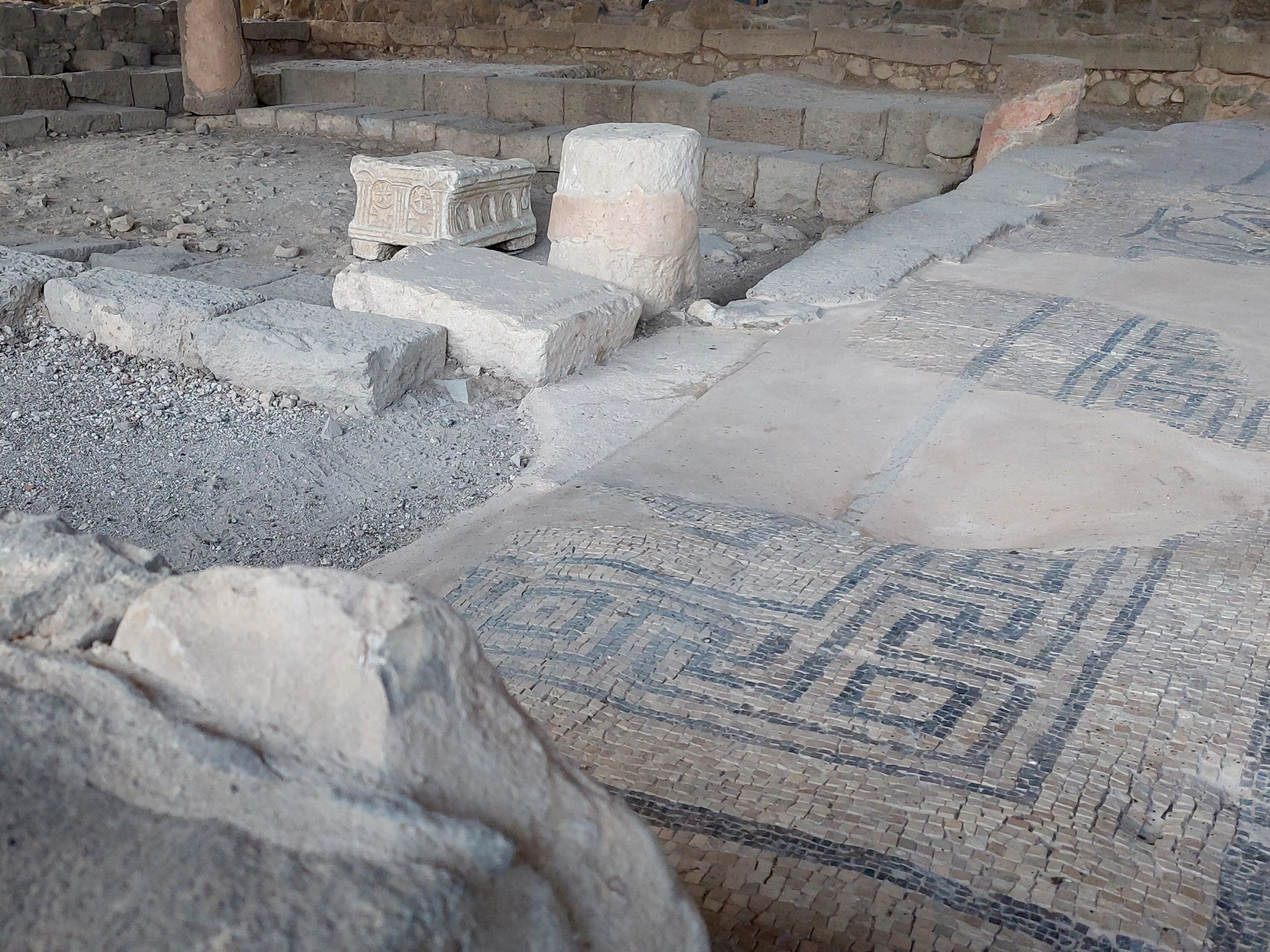 Ancient mosaic floor and stone column bases inside the ruins of the synagogue of Magdala