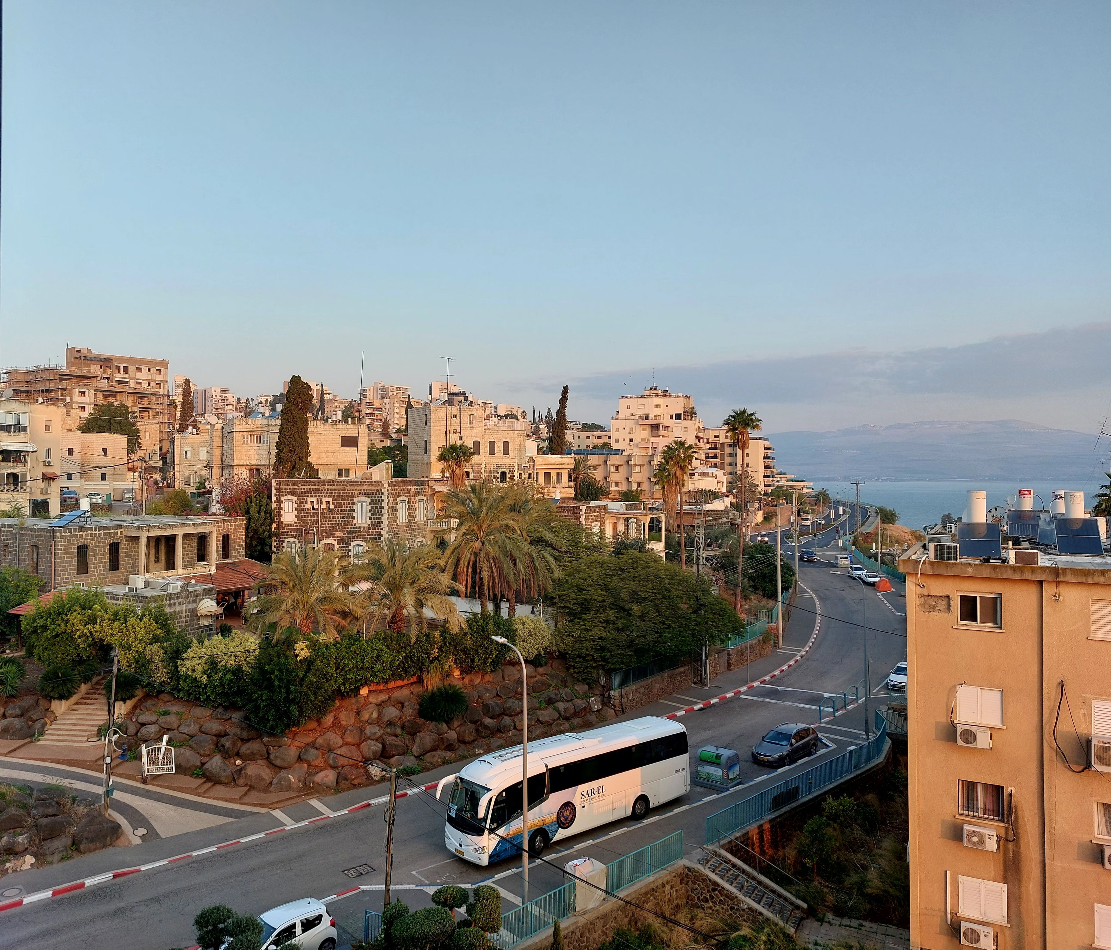 The city of Tiberius on the shores of the Sea of Galilee with buildings, palm trees and a bus on the road