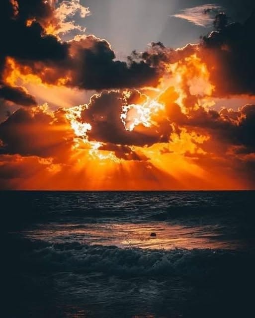 Dramatic sunset with golden rays breaking through storm clouds over the ocean