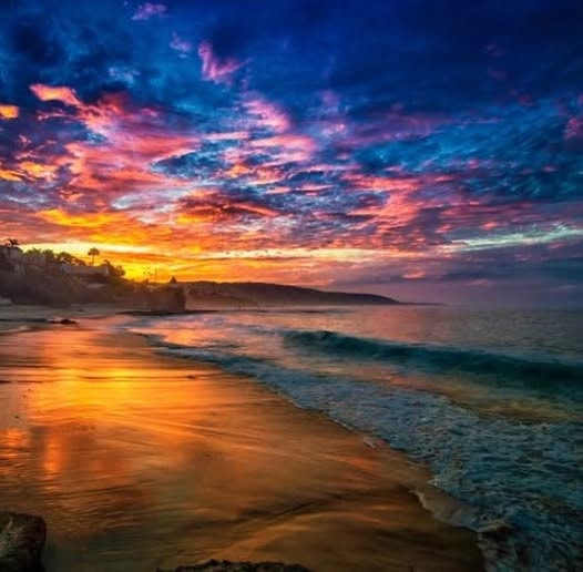 Vibrant sunset over the ocean with golden light reflecting on the beach