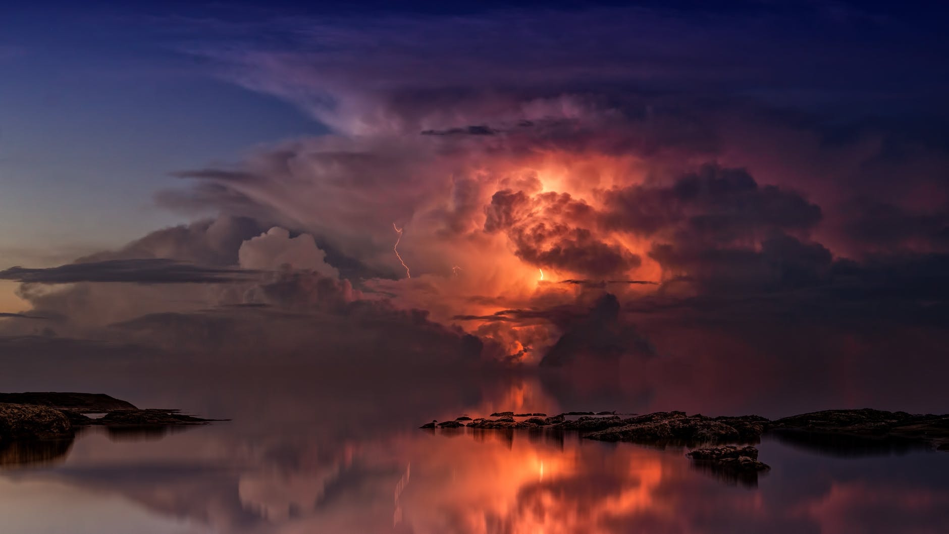 Lightning storm over water reflecting dramatic sky