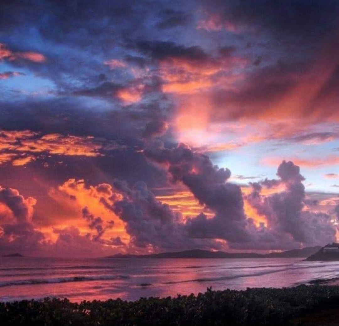Dramatic sunset over tropical beach with vivid orange and purple clouds