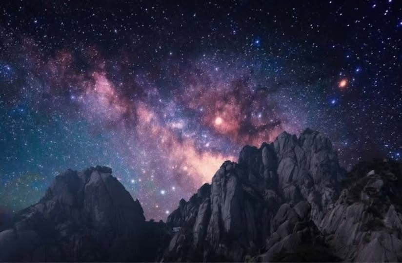 Milky Way galaxy blazing over dramatic rocky mountain peaks at night