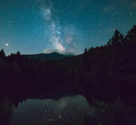Milky Way galaxy reflected in a still mountain lake at night