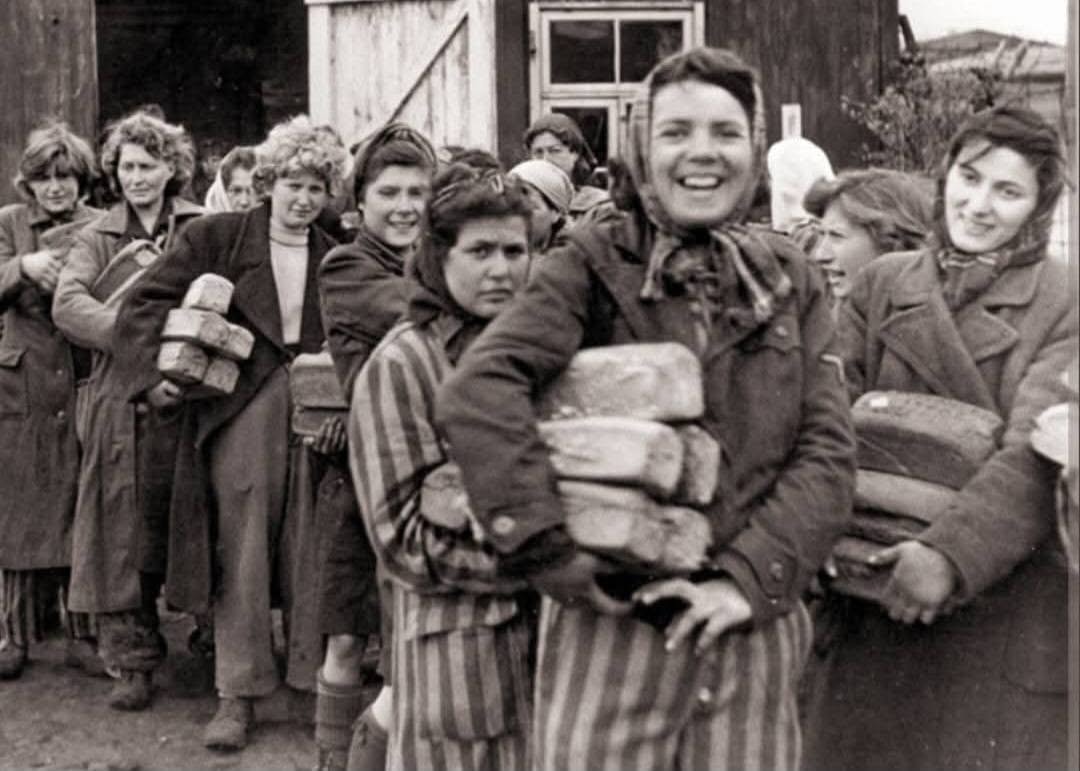 Liberated women prisoners at Dachau carrying bread after liberation, April 1945