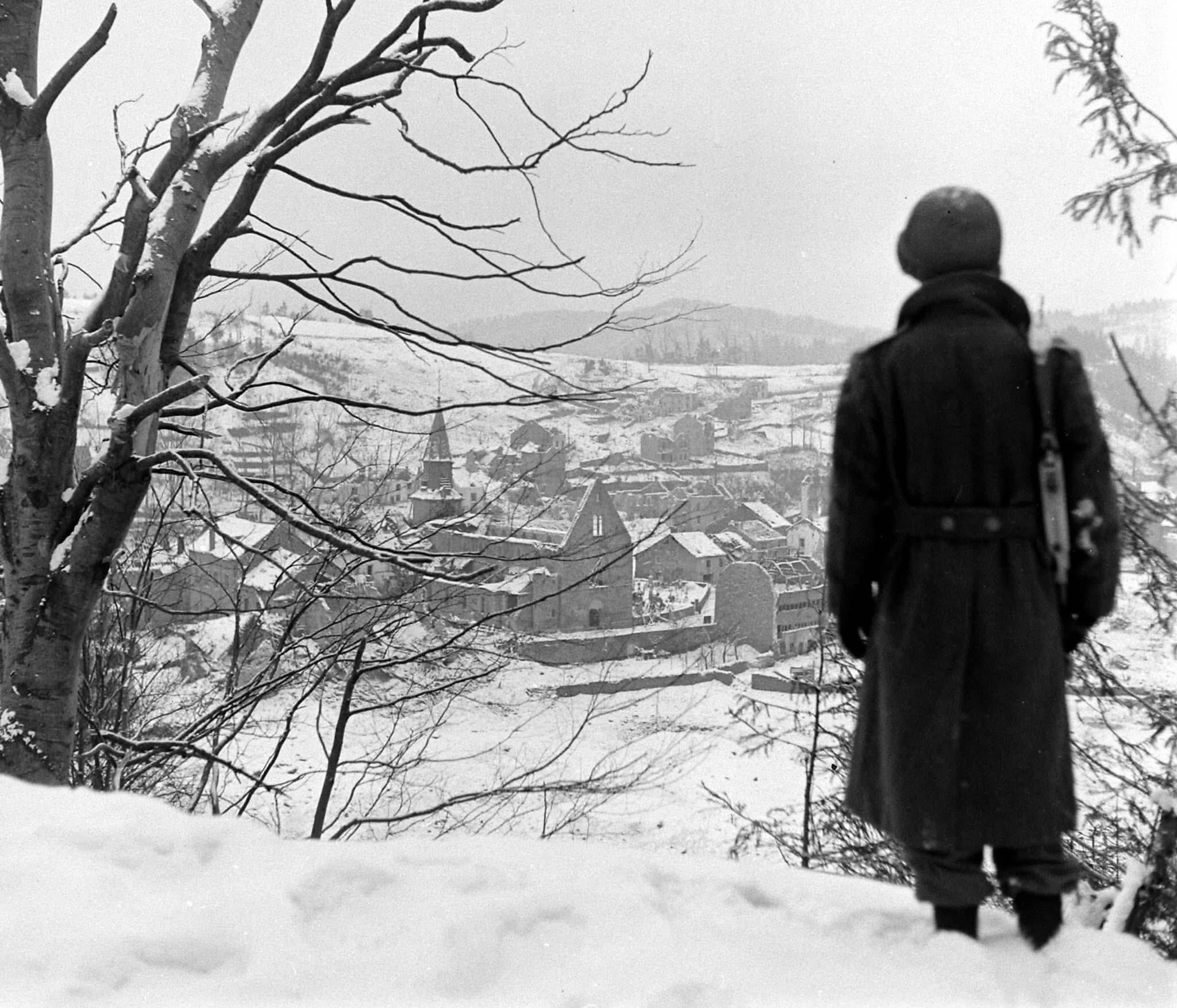 American soldier overlooking a snow-covered French village during the Vosges Mountains campaign